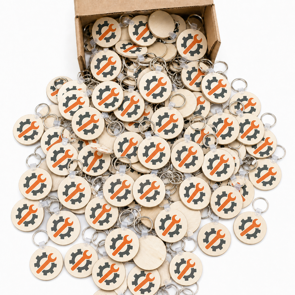 Bulk order of round birch keychains printed with an orange and grey logo, spilling from a kraft box