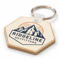 Close-up of a hexagon birch wood keychain printed with a navy and orange mountain logo, showing the bare plywood edge and split ring