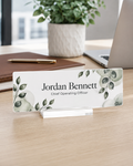 Custom acrylic desk name plate, greenery design with name and title in full color, on a clear slotted base on a modern office desk