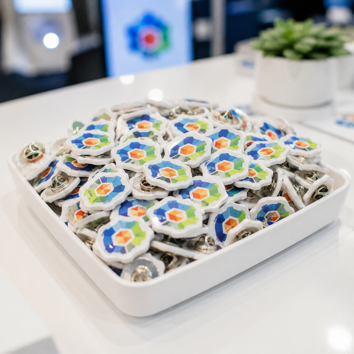 Tray of custom white acrylic logo lapel pins as trade-show swag
