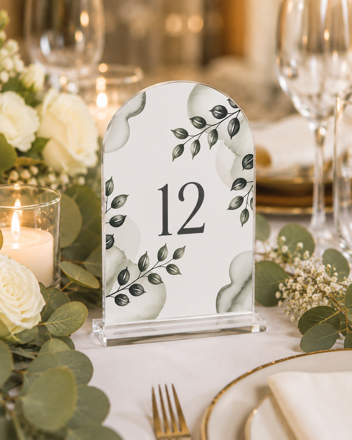 Custom acrylic arch-top table number, full-color greenery design, number 12, on a clear acrylic display stand at a wedding table