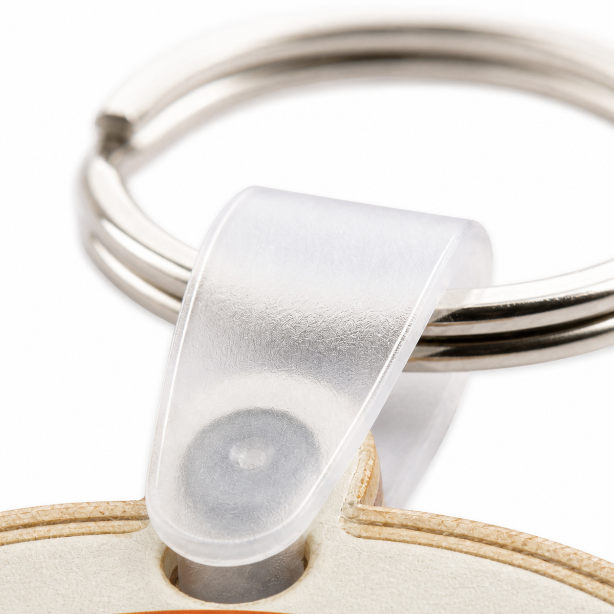 Macro detail of the clear plastic connector and stainless steel split ring attached to a birch wood keychain
